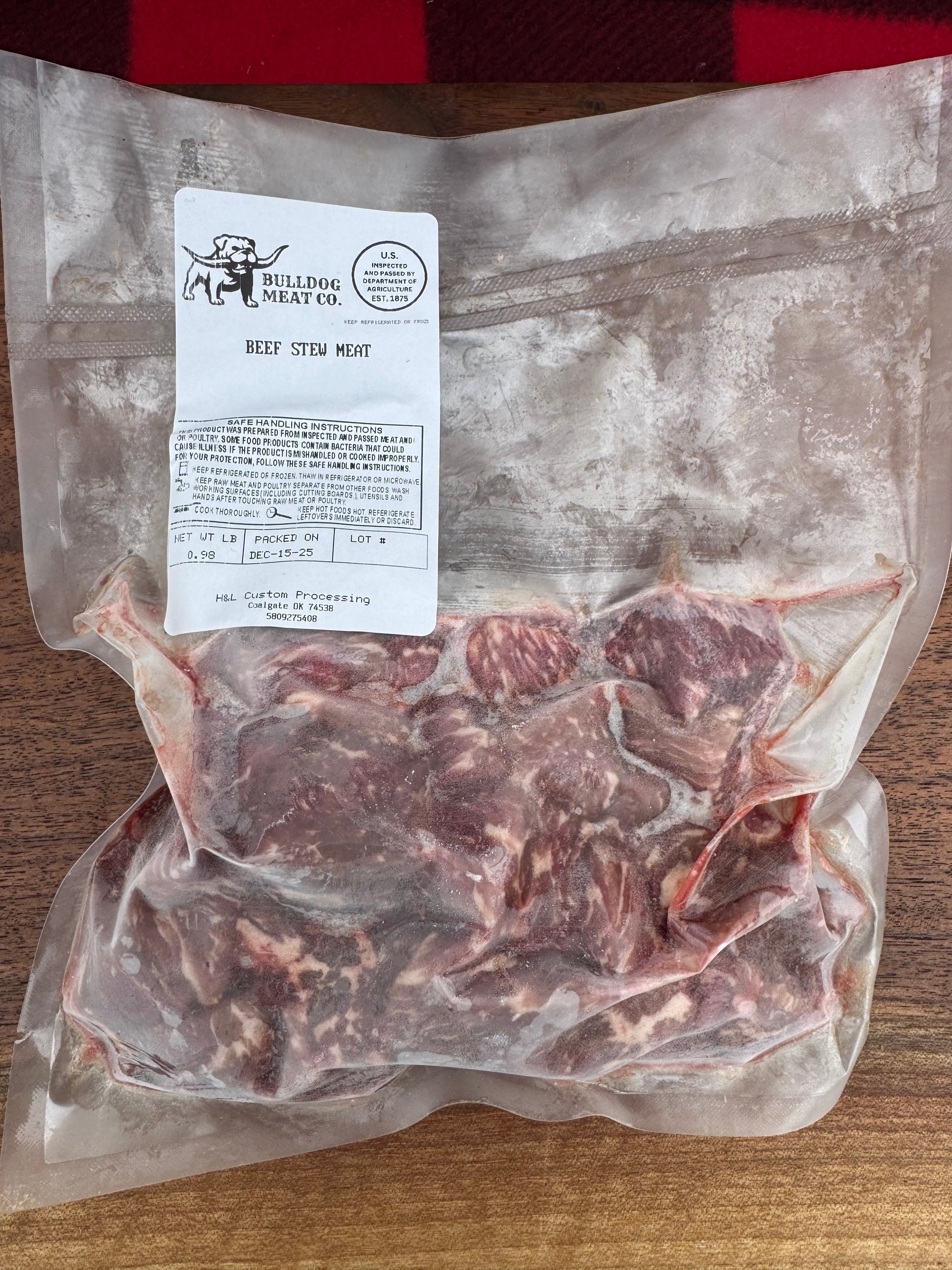 Vacuum-sealed package of raw meat with a label on a wooden surface