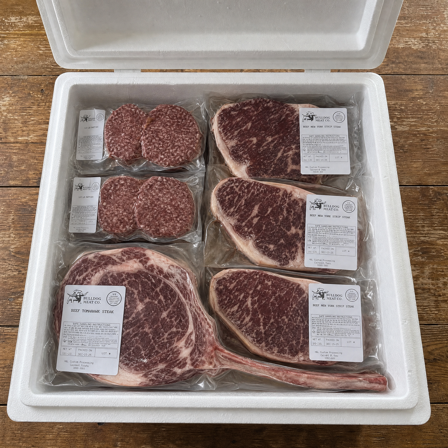 Packaged meat including steaks and burgers in a white container on a wooden surface