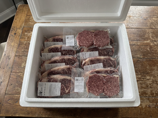 Frozen meat packages in a white cooler on a wooden surface