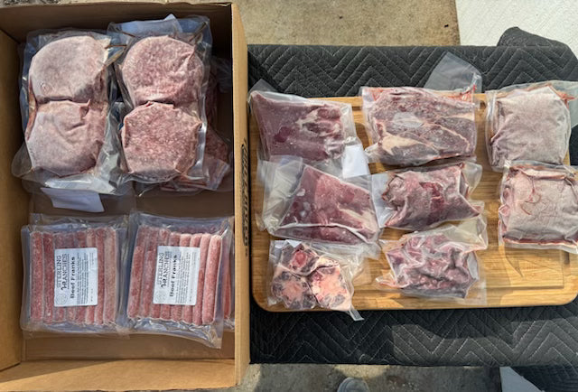 Frozen meat packages in clear plastic on a cardboard box and wooden cutting board.